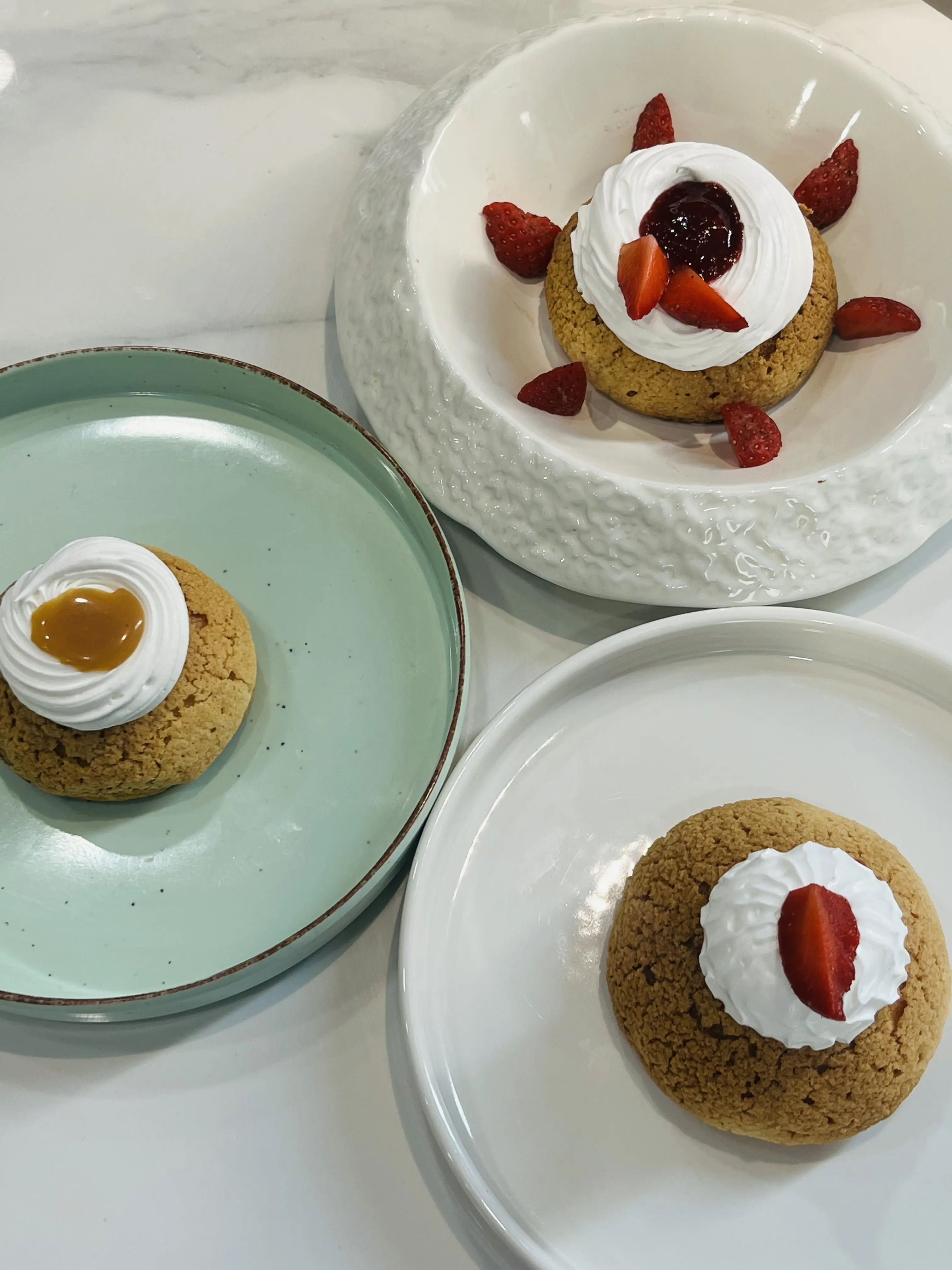 Plated panna-cotta desserts crowned with cream and fresh strawberries