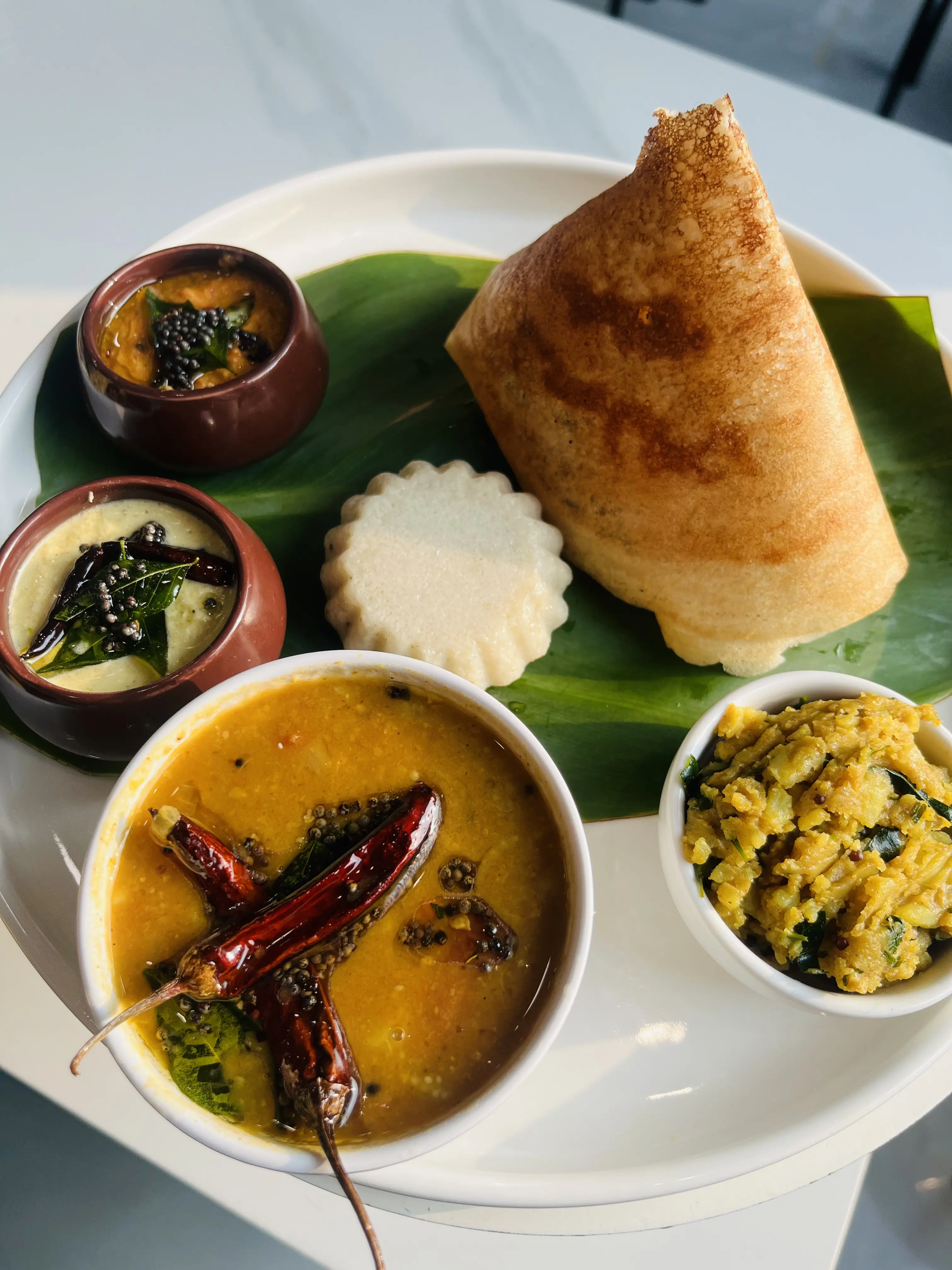 South Indian thali — crisp dosa, sambar and chutneys on a banana leaf